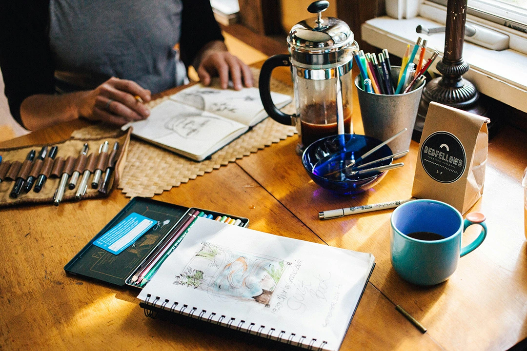 person sketching with coffee at a cozy café windsor.